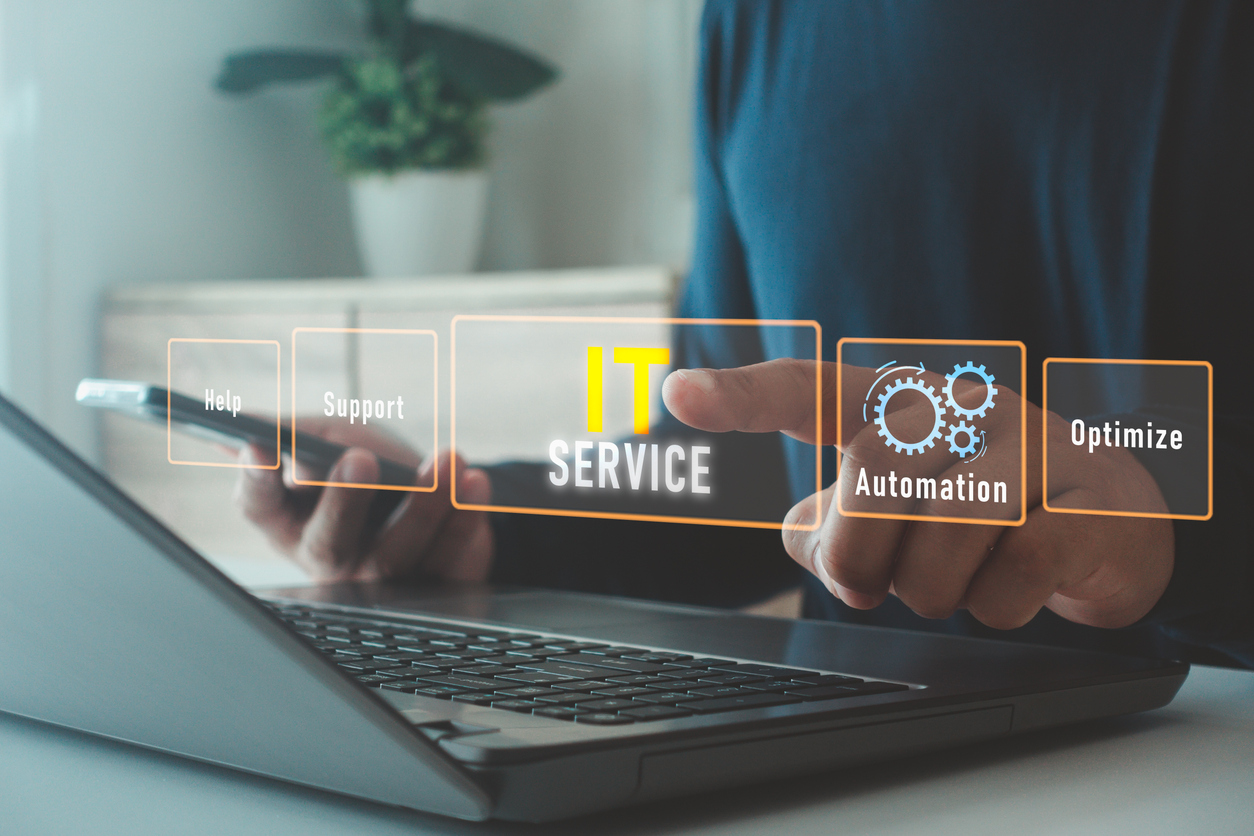 IT services professional using laptop and tablet with digital interface showing help, support, automation, and optimization solutions